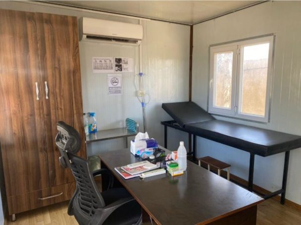 Krankenzimmer mit Schreibtisch, Stuhl, Schrank und Krankenliege