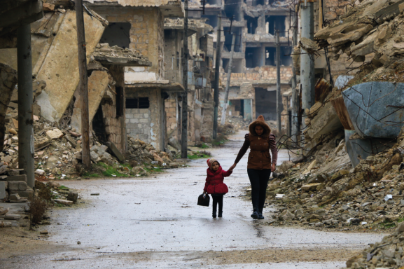 Mutter und Tochter laufen durch die zerstörte Stadt